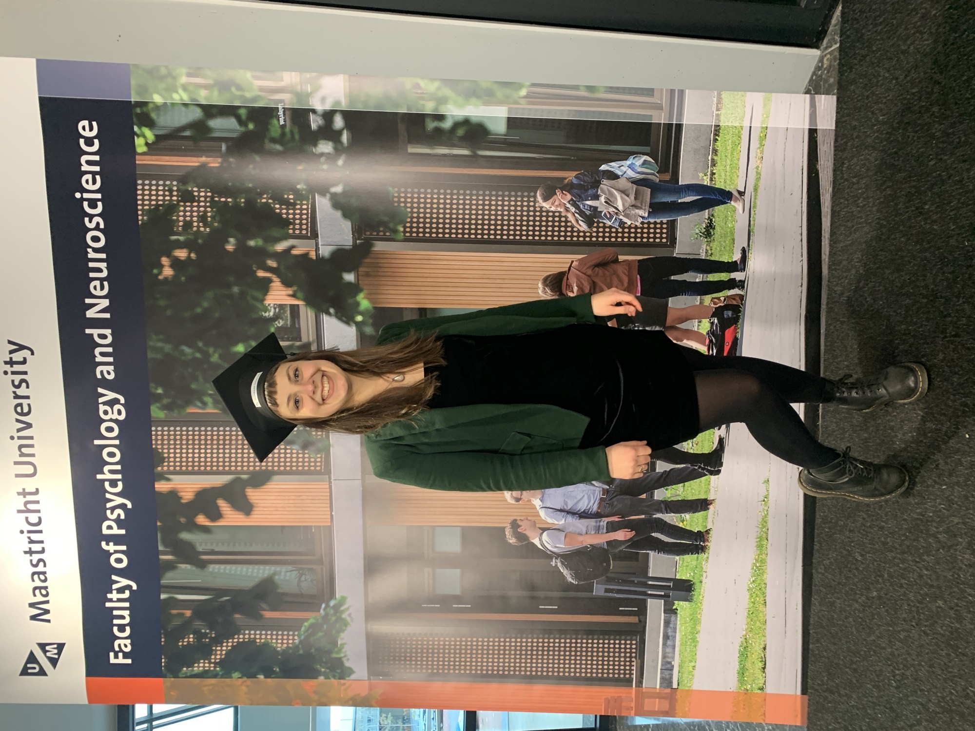 Judith mit Doktorhut vor Maastricht University Schild